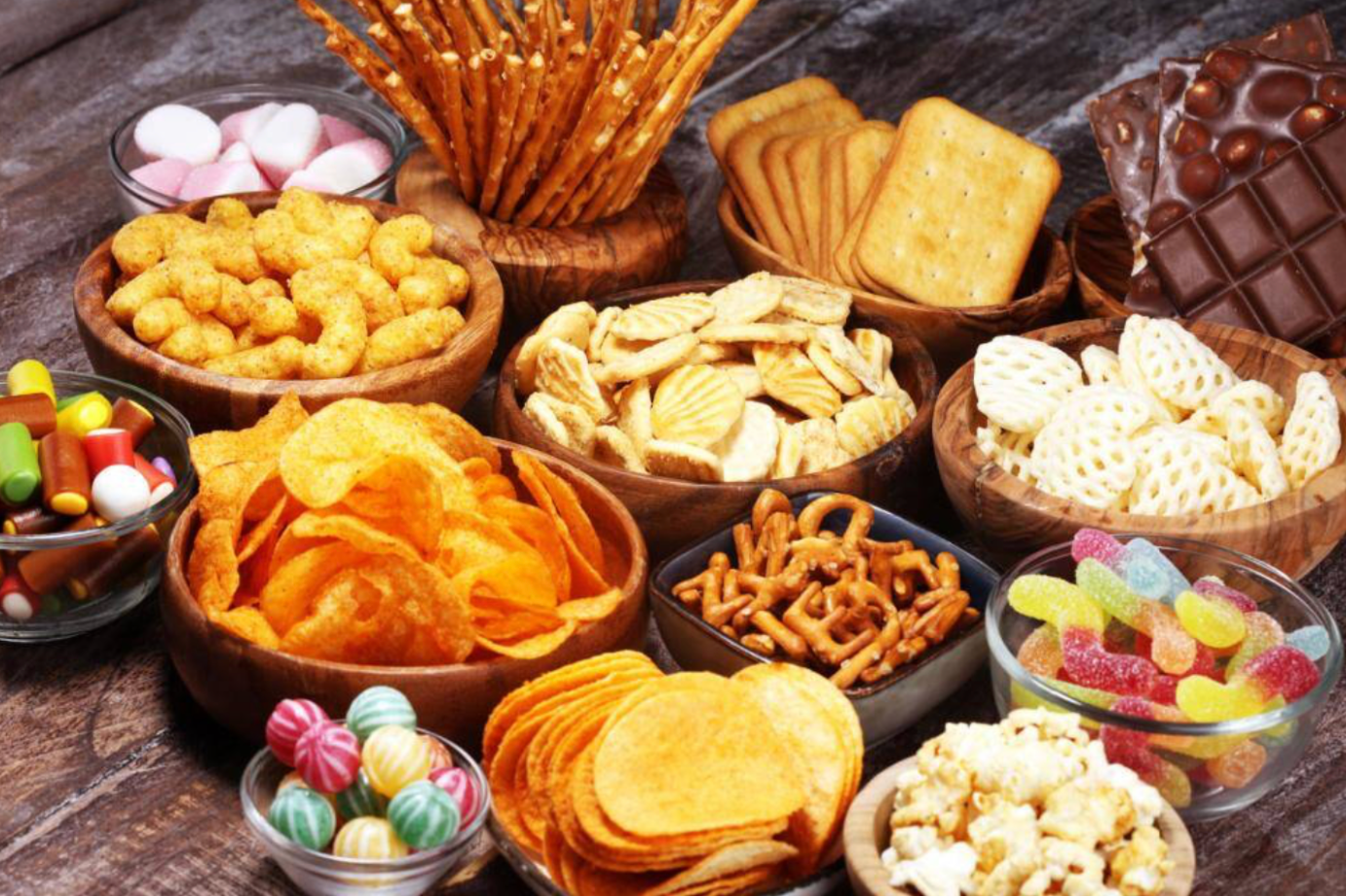 Alimentos industrializados como salgadinhos e refrigerantes em mesa.