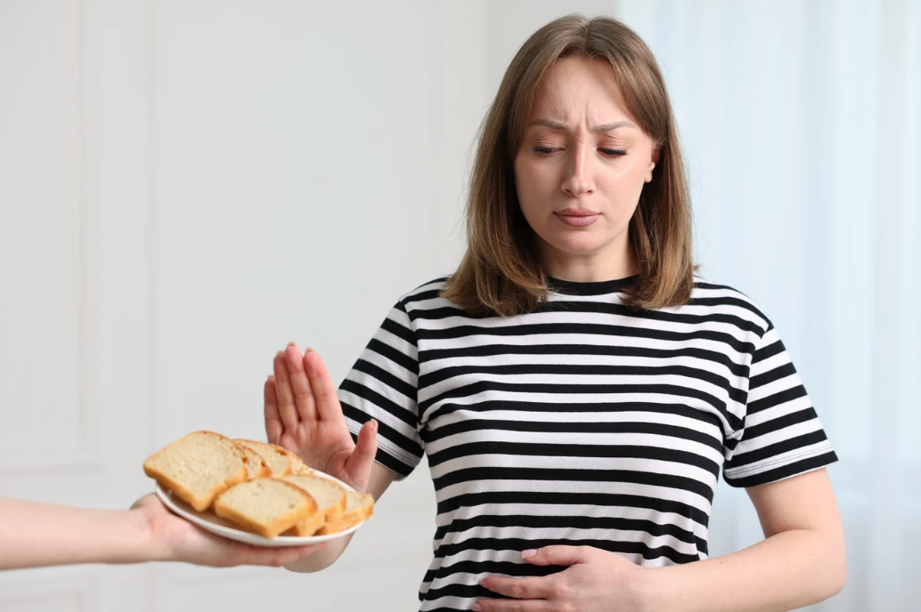 Pessoa fazendo gesto de recusa diante de prato com pão.