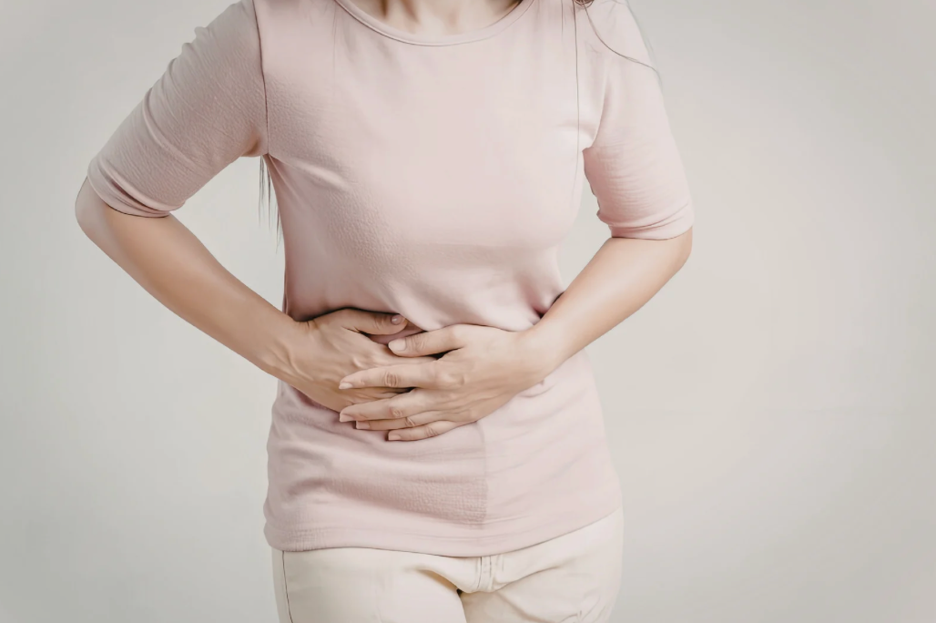 Mulher segurando o abdômen após comer, demonstrando desconforto digestivo.